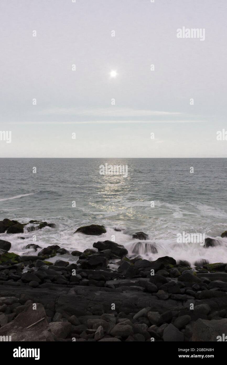 Either the sun or a full moon shines on a clear sky over the sea and ...