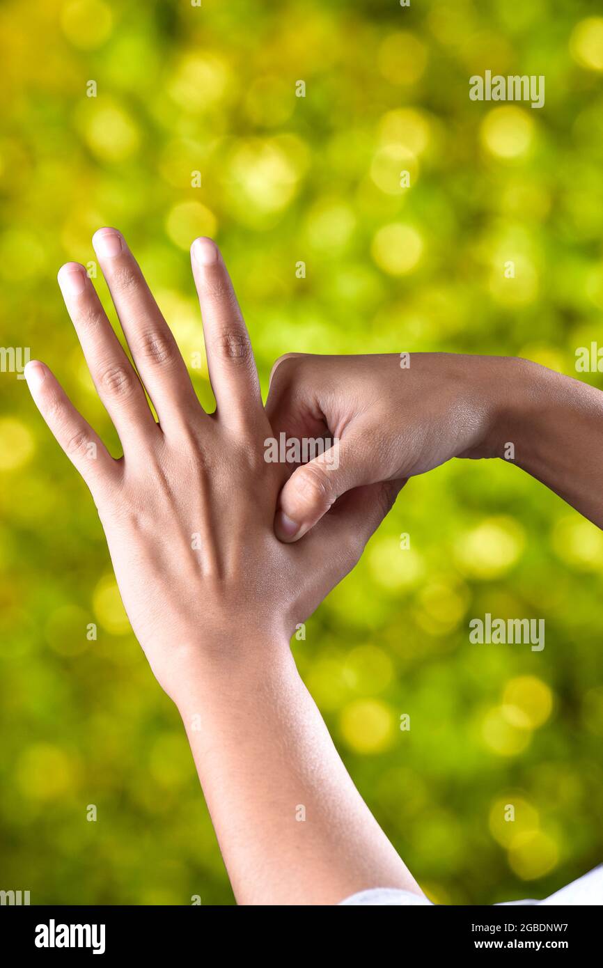 female hands make acupressure on the arm against beautiful green background, health concept Stock Photo