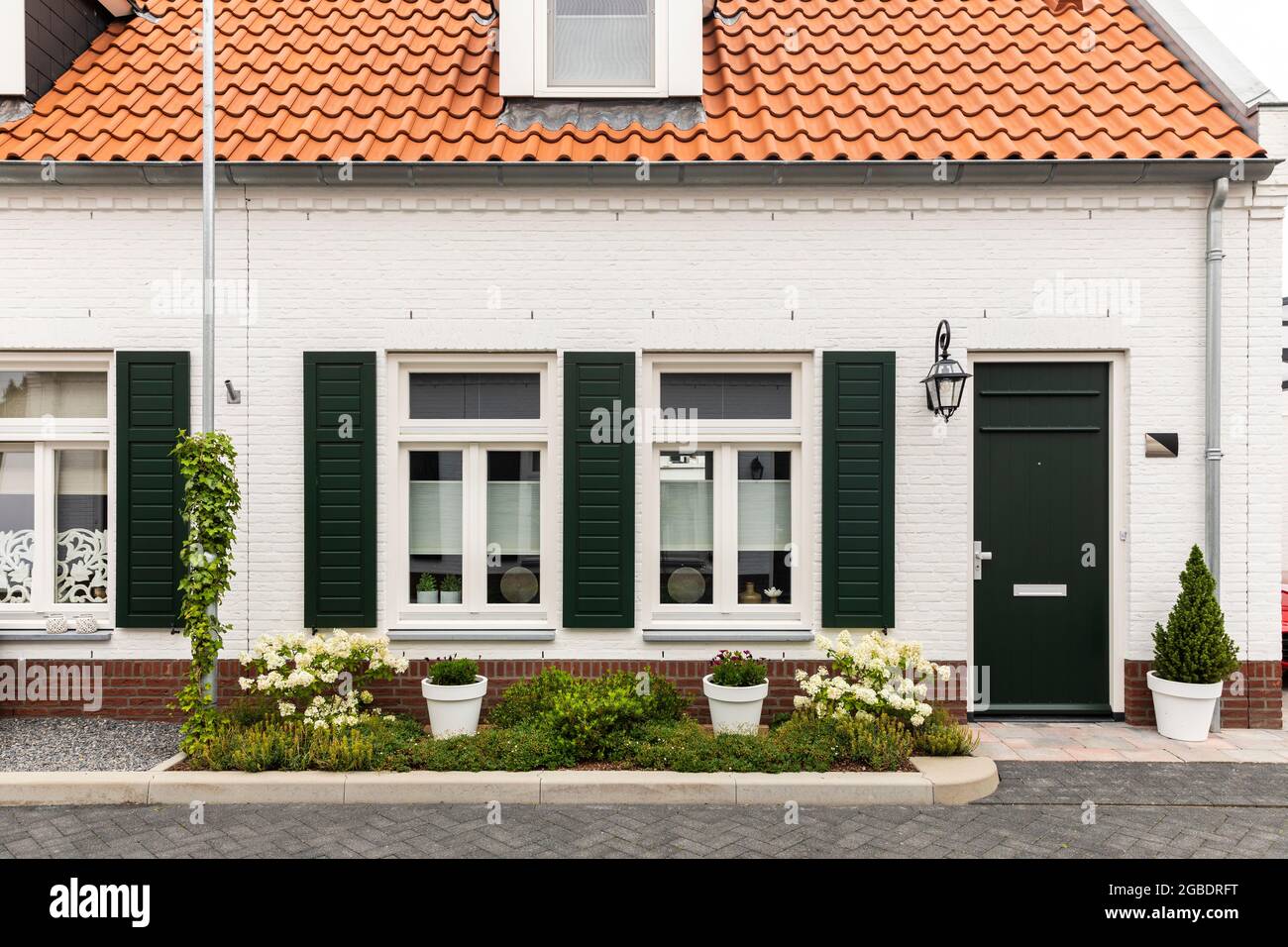 Symmetrical facade of a white modern house with an orange roof in Thorn