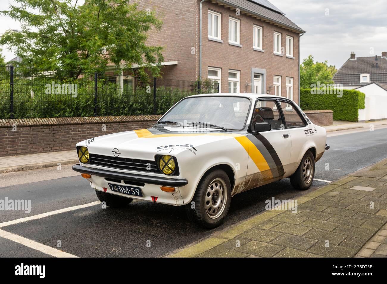 Thorn, The Netherlands, June 24th 2021. A white Opel Kadett yountimer car with yellow, grey and black stripes parked in a street with houses and green Stock Photo