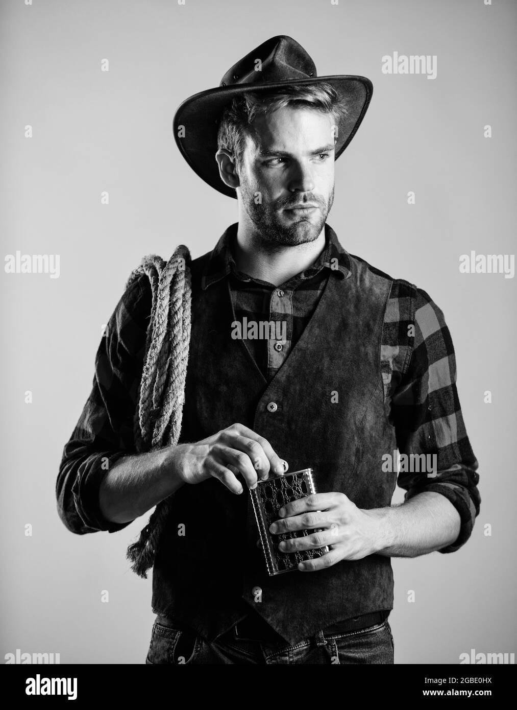 Sheriff concept. Brutal cowboy drinking alcohol. Man handsome cowboy beige background. Western life. Bourbon whiskey. Western culture. Man wearing hat Stock Photo