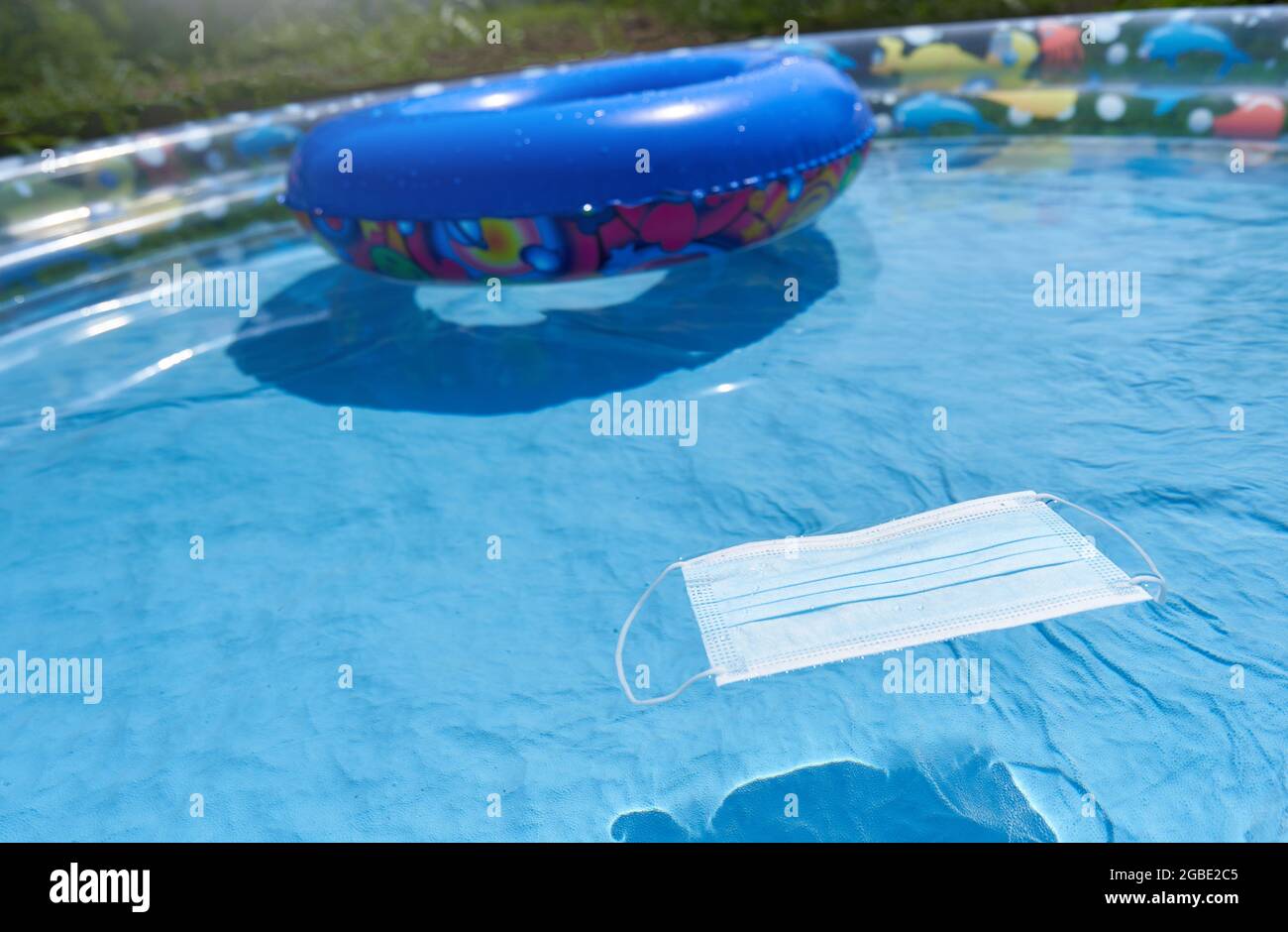 Protective mask in a children's inflatable pool, the concept of a seaside holiday and the coronavirus pandemic Stock Photo