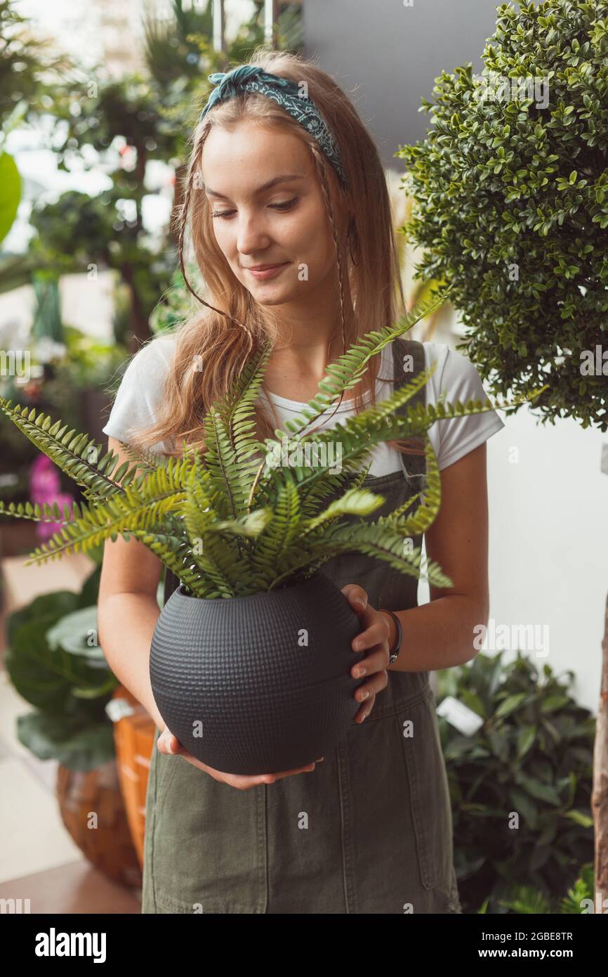 Woman in greenhouse with fern in pot. Stock Photo