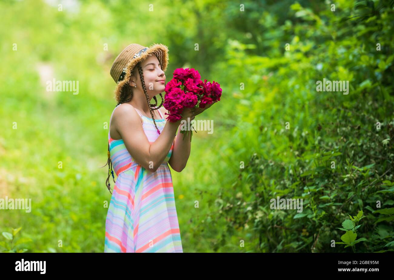happy child girl in straw hat with rose flowers in summer nature ...