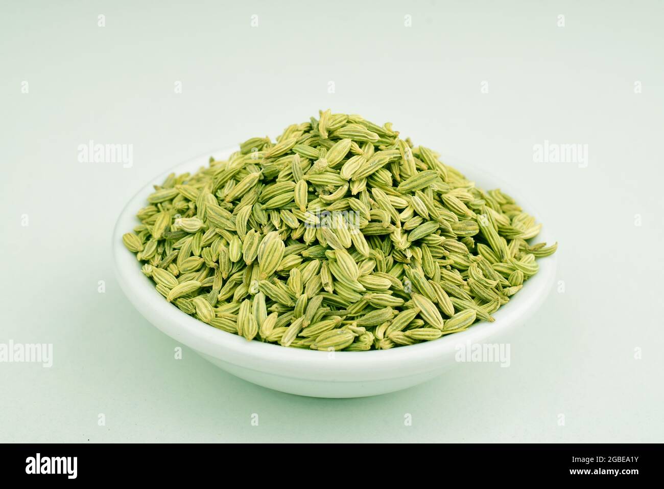 Fennel Seeds In Bowl Over White Background Stock Photo