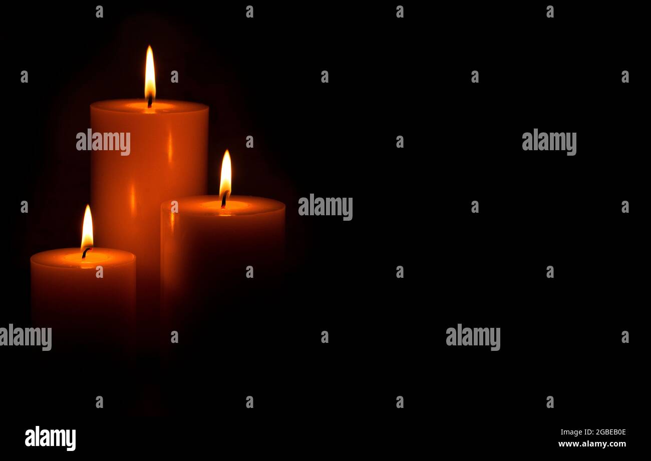 Three Pillar Candles Lit in a Dark Room Stock Photo