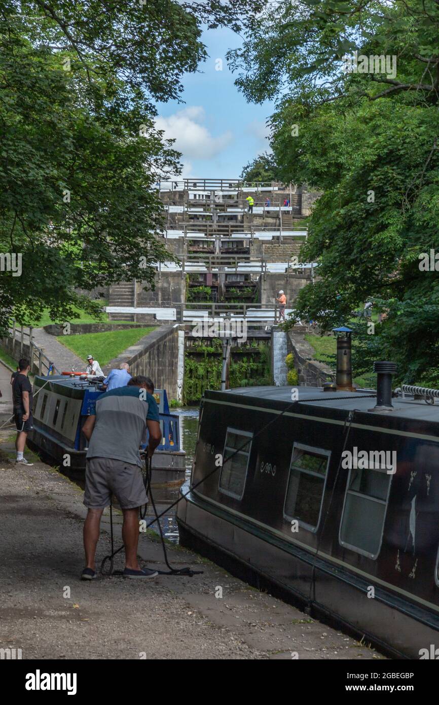 A man moors up his barge (narrowboat) on the Leeds Liverpool Canal at the bottom of the Five Rise Locks in Bingley, Yorkshire. Stock Photo