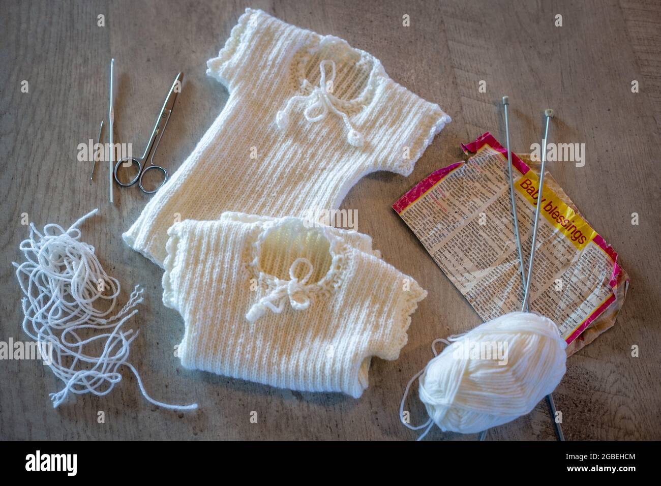Woollen baby merino singlets are hand knitted with crochet edging in preparation for a new baby Stock Photo