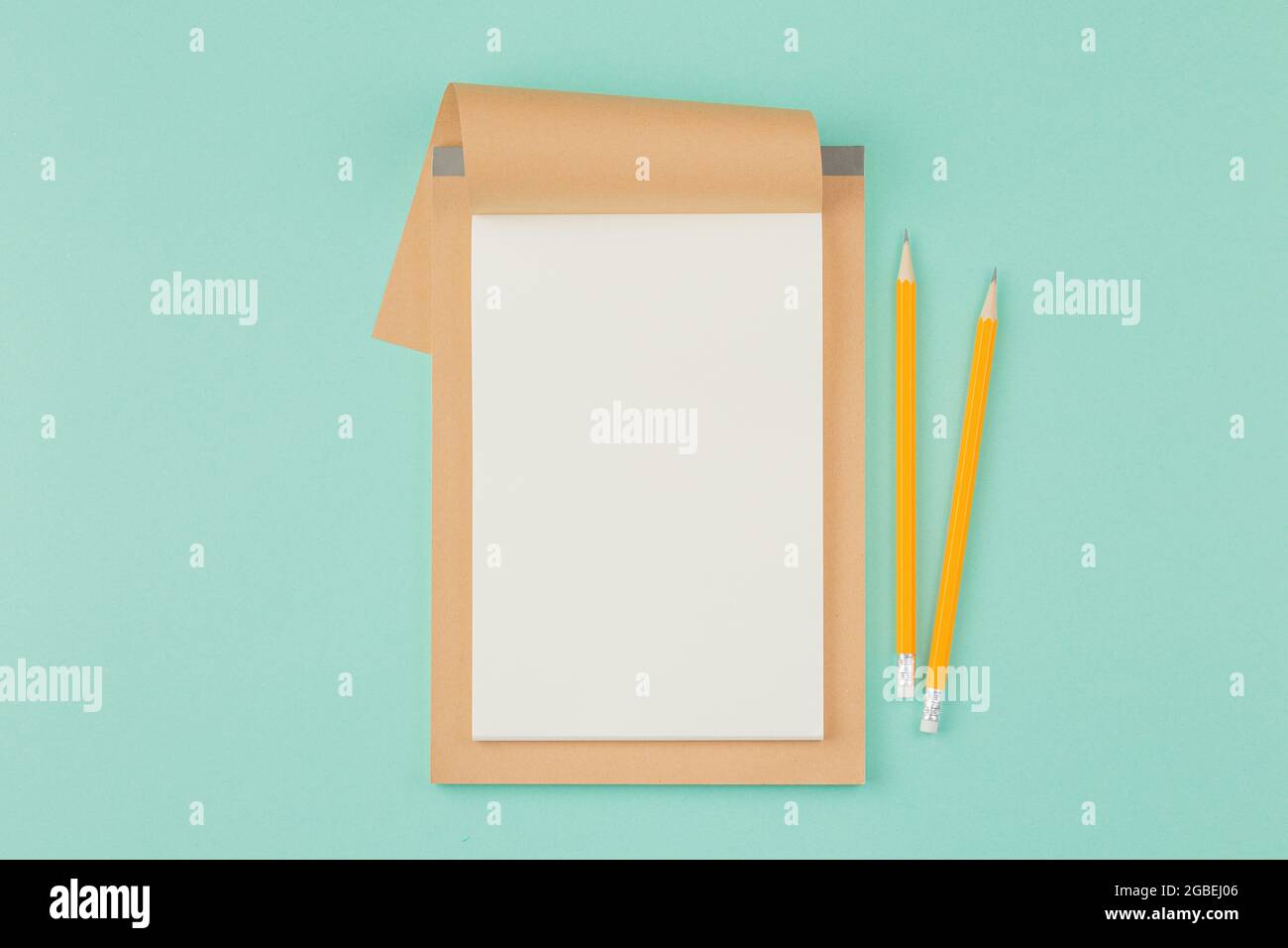 Open notepad with pencil on cyan background. Stock Photo