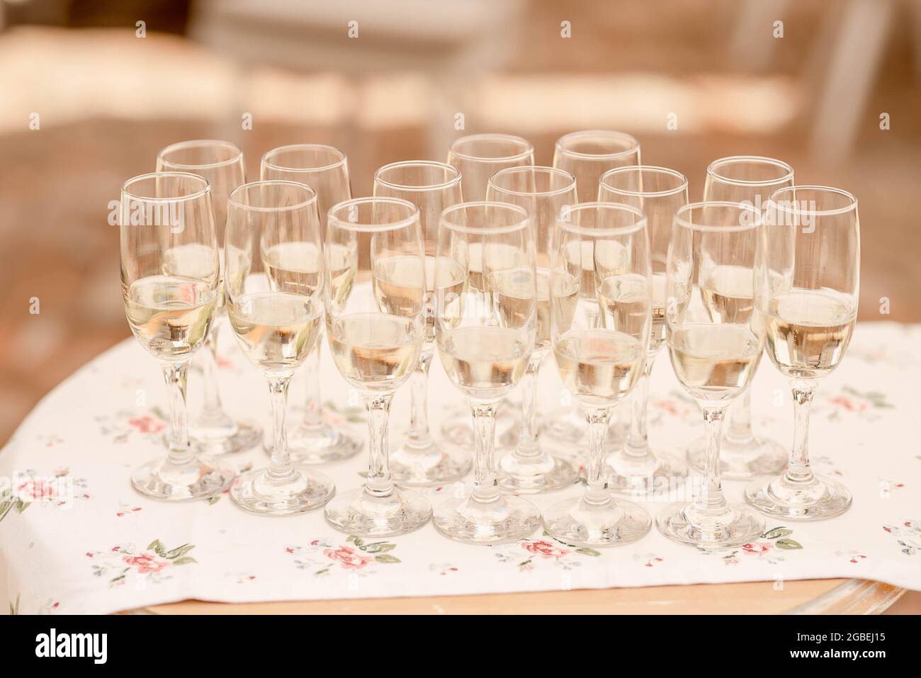 Champagne flutes half full with a bubbly fizzy alcoholic drink set on a large trey, sparkling wine in long glasses prepared for the wedding guests Stock Photo