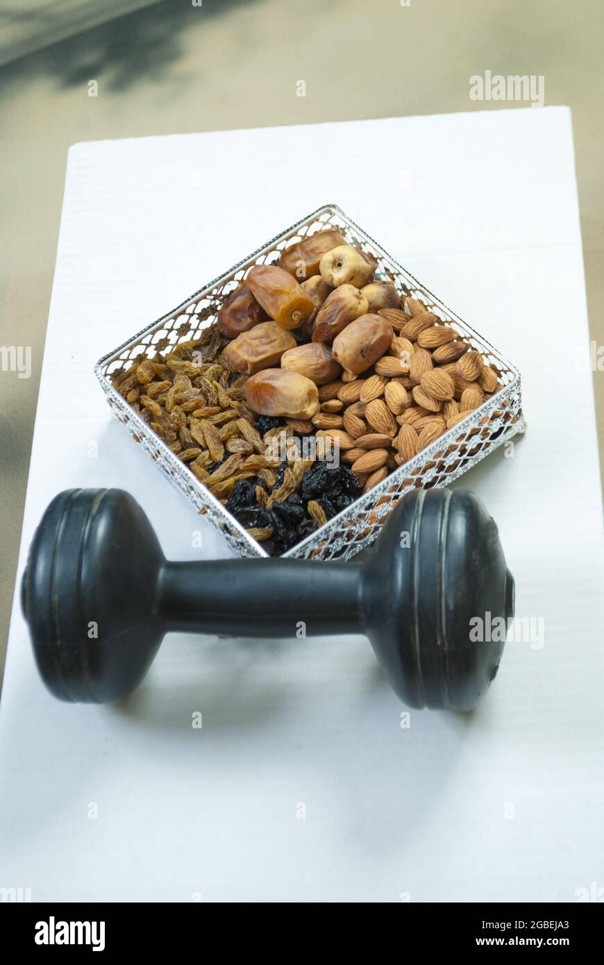 gym workout food organic healthy mix dry fruits with dumbbell golden and black raisins dates almonds exercise concept space for text Stock Photo