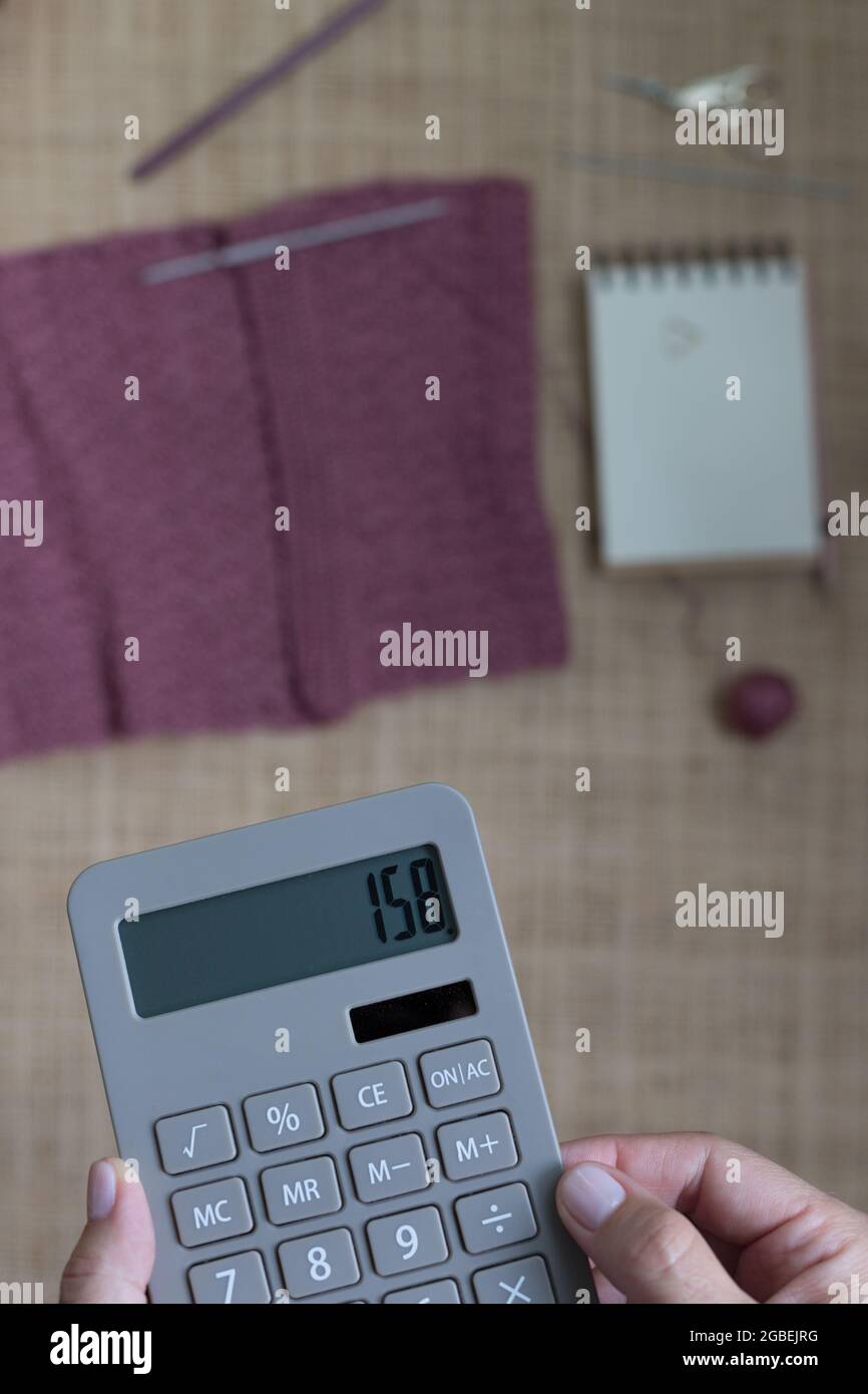 Closeup view of a domestic calculator held by a white woman with the number of crochet points estimated. Stock Photo