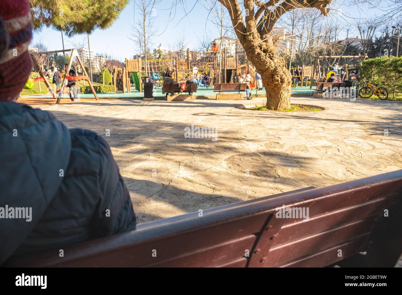 Kadikoy, Istanbul, Turkey - 02.03.2021: an unrecognizable cold child looks at people playing in Kadikoy freedom park with copy space Stock Photo