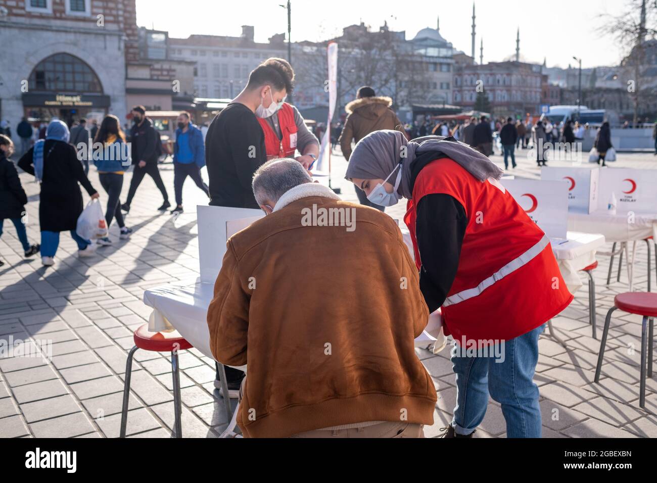 Eminonu, Istanbul, Turkey - 02.26.2021: medium shot of female employee of Turkish Red Crescent helps blood donation volunteer Stock Photo