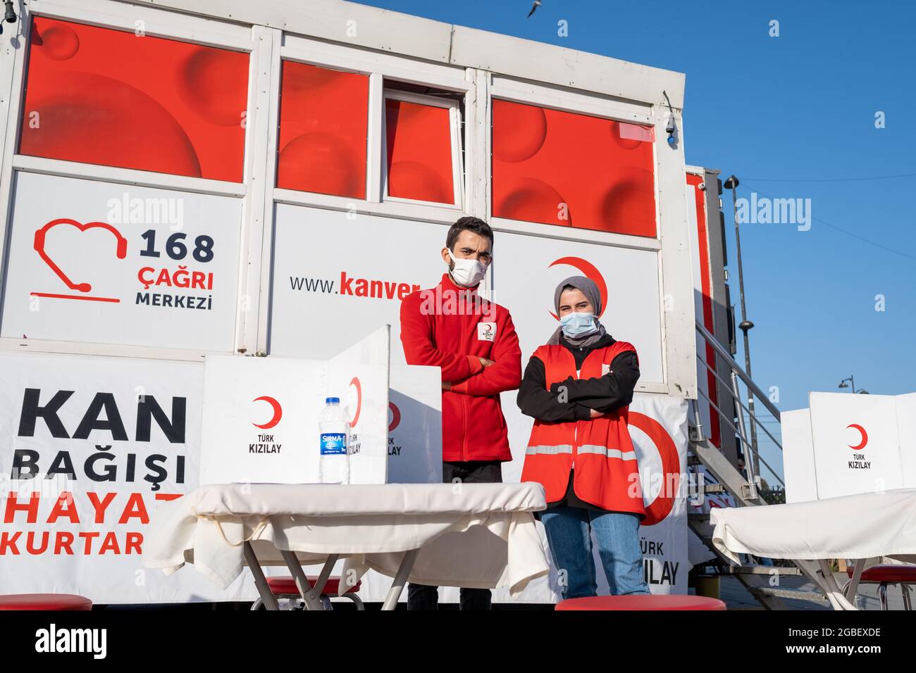 Eminonu, Istanbul, Turkey - 02.26.2021: man and woman employees of Turkish Red Crescent (Türk Kizilay) in front of blood donation vehicle. Translation Stock Photo