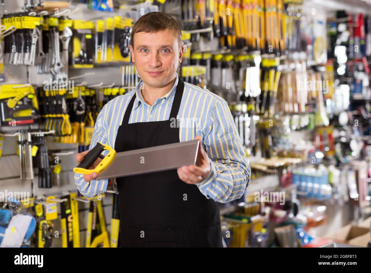 Man seller in apron having tools in hands Stock Photo