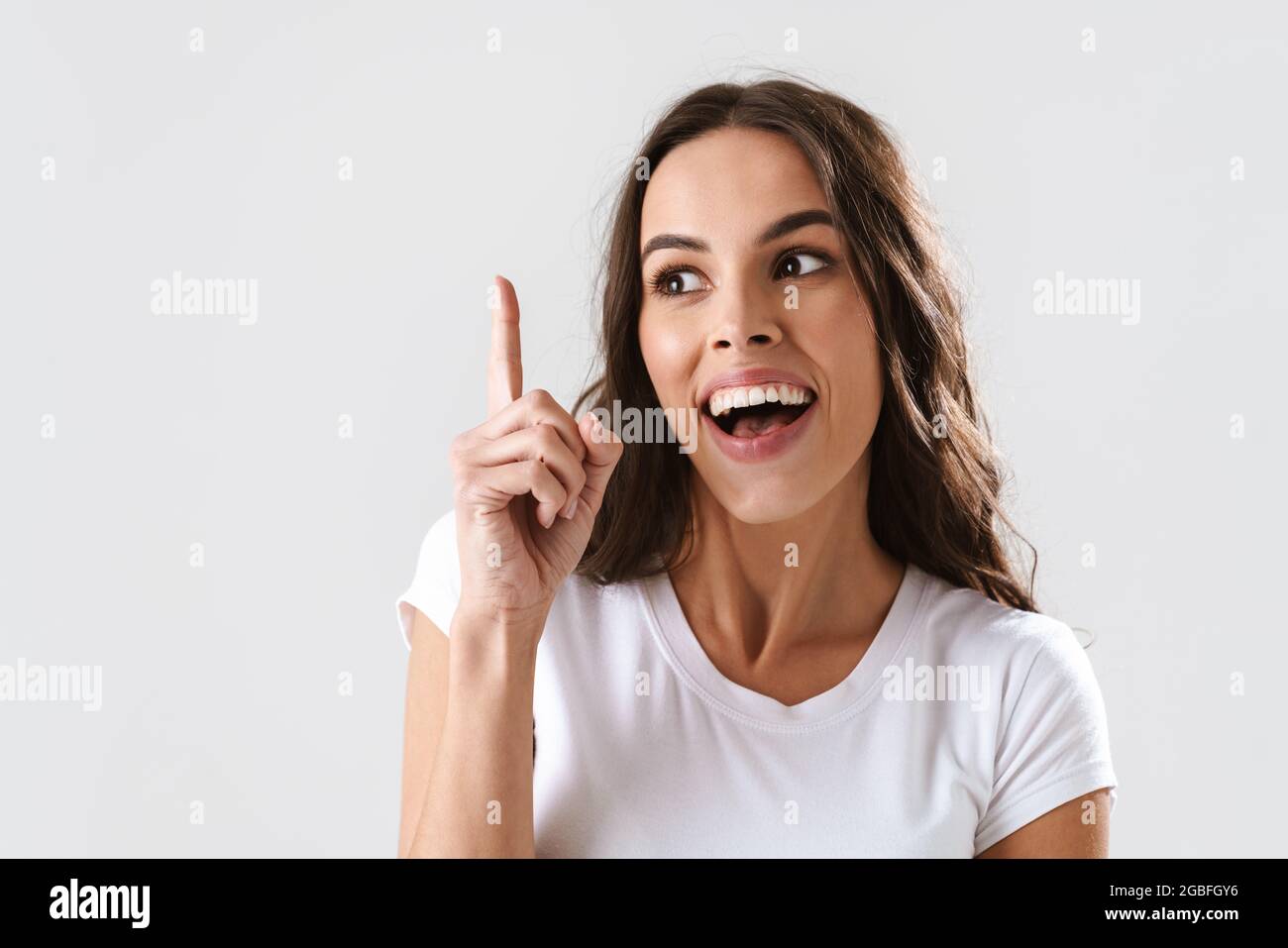Excited beautiful girl smiling and pointing finger upward isolated over ...