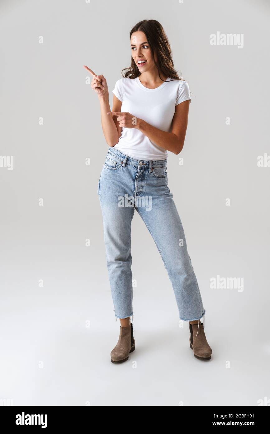 Joyful beautiful girl smiling and pointing fingers aside isolated over ...