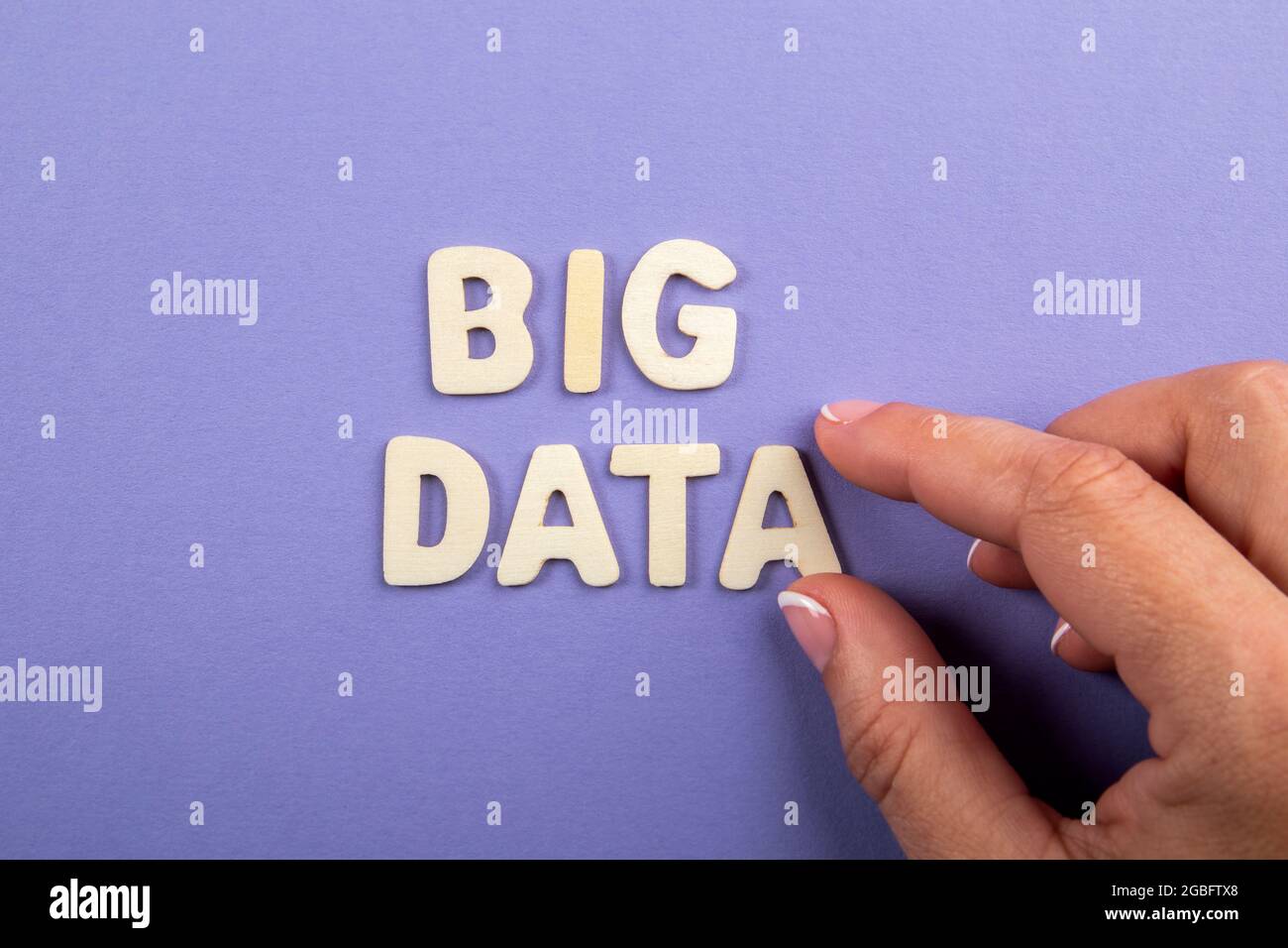 BIG DATA. White wooden letters with text and a woman's hand on a purple background. Stock Photo