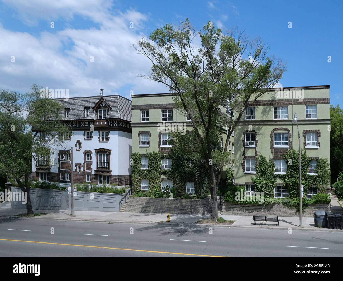 Old style small low rise apartment buildings on a main street, covered in vines Stock Photo