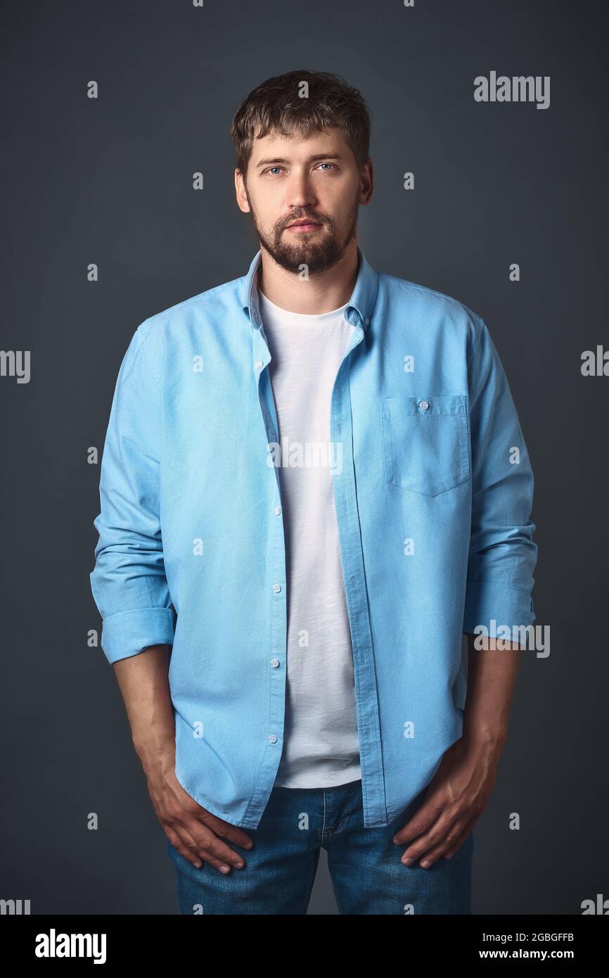 This young confident man with a beard in stylish casual clothes poses ...