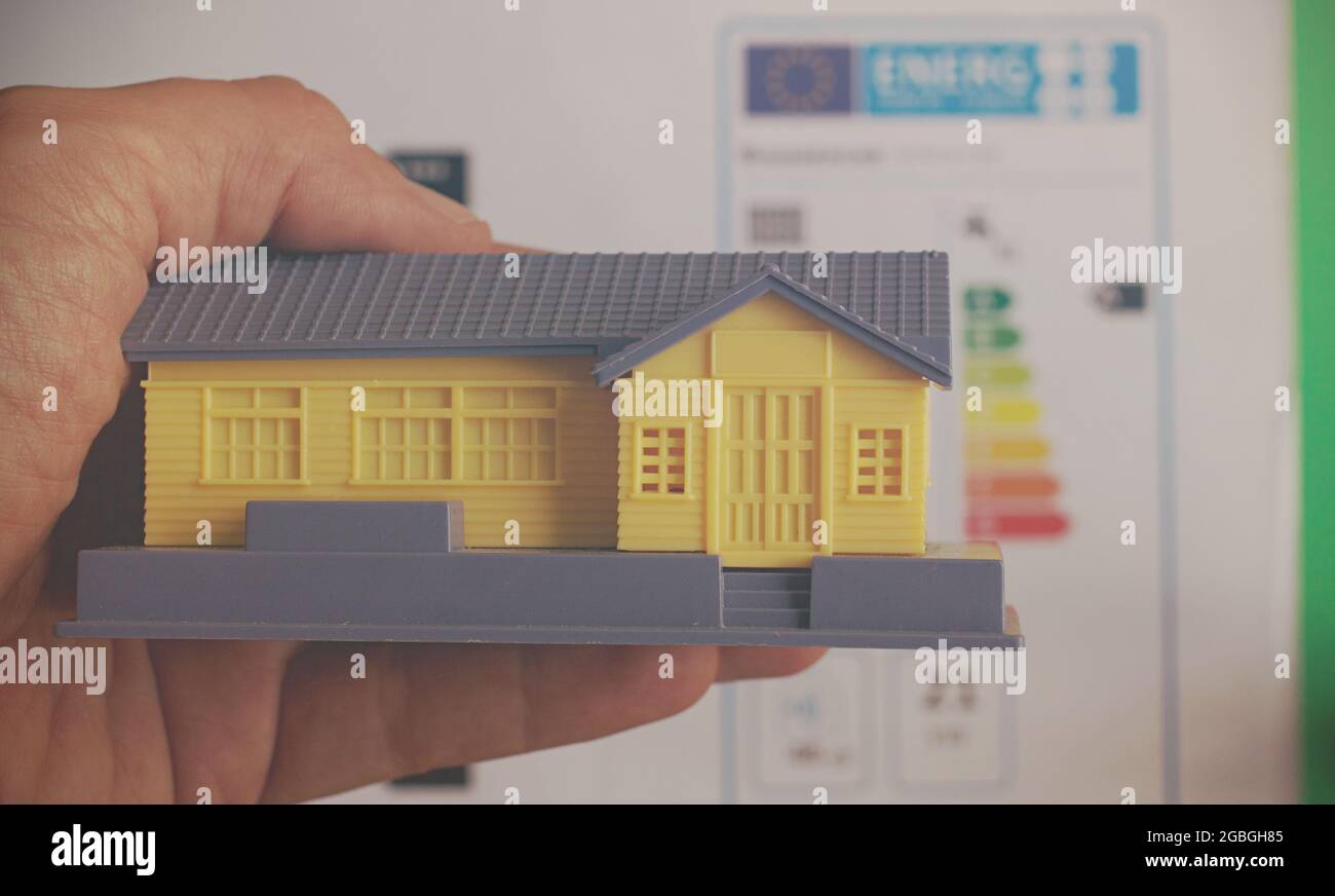 Hand holding a house with a classification graph as background, energy
