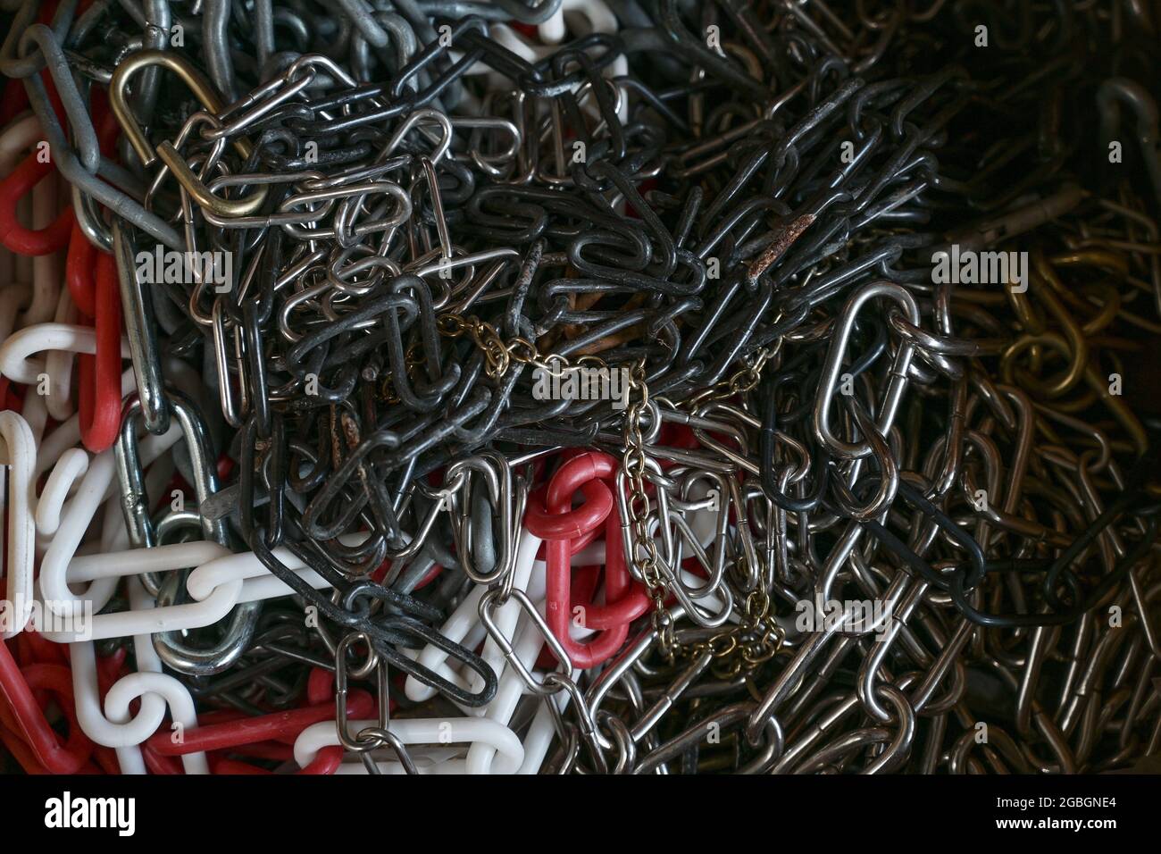 Different chains from metal and plastic in a workshop as full frame background texture, copy space, selected focus, narrow depth of field Stock Photo