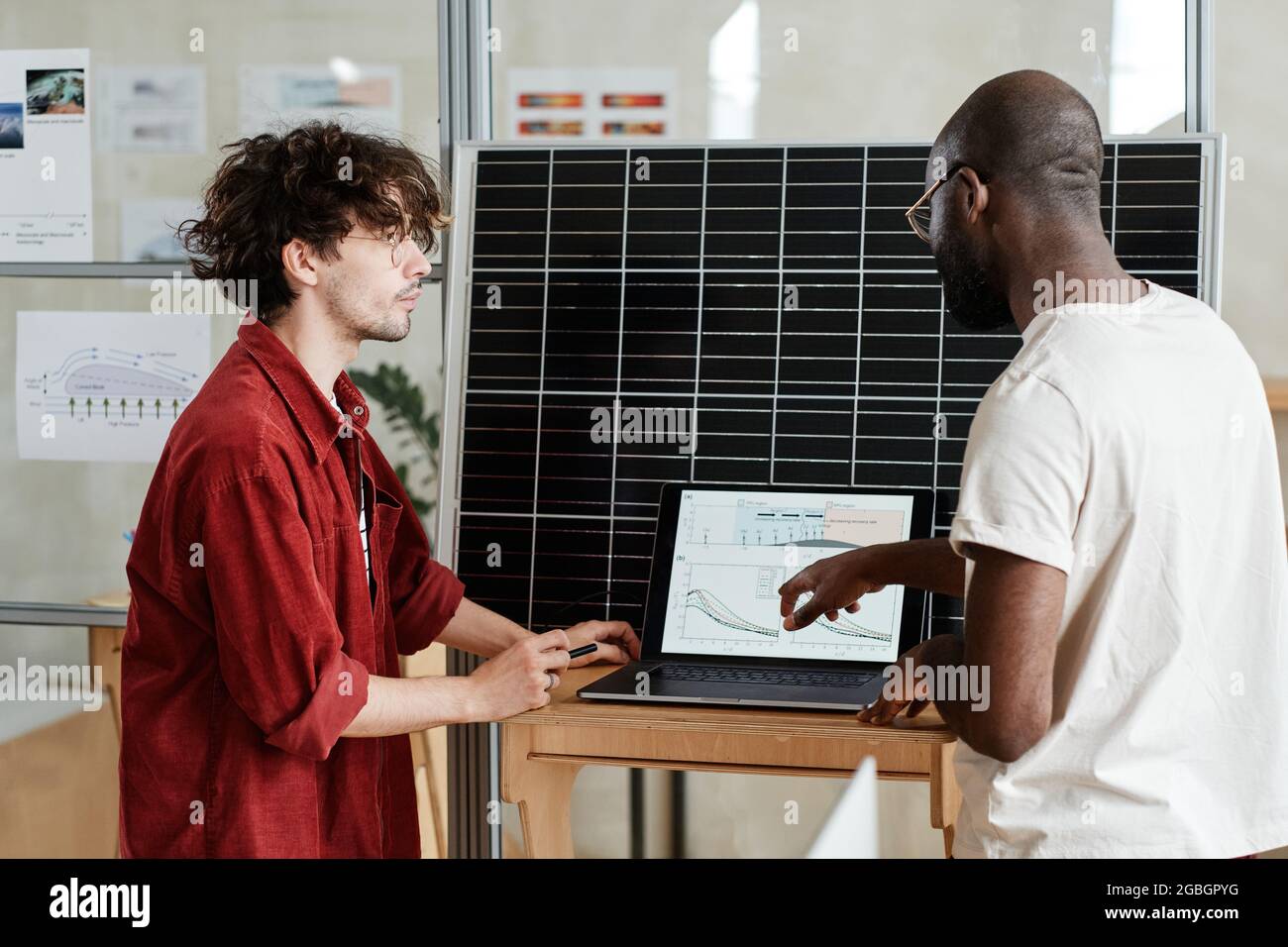 Two designers sitting at the table in front of laptop and developing new project online at office Stock Photo