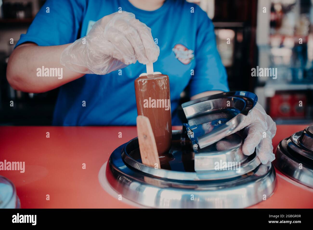 an ice cream vendor dips a popsicle in liquid chocolate Stock Photo Alamy