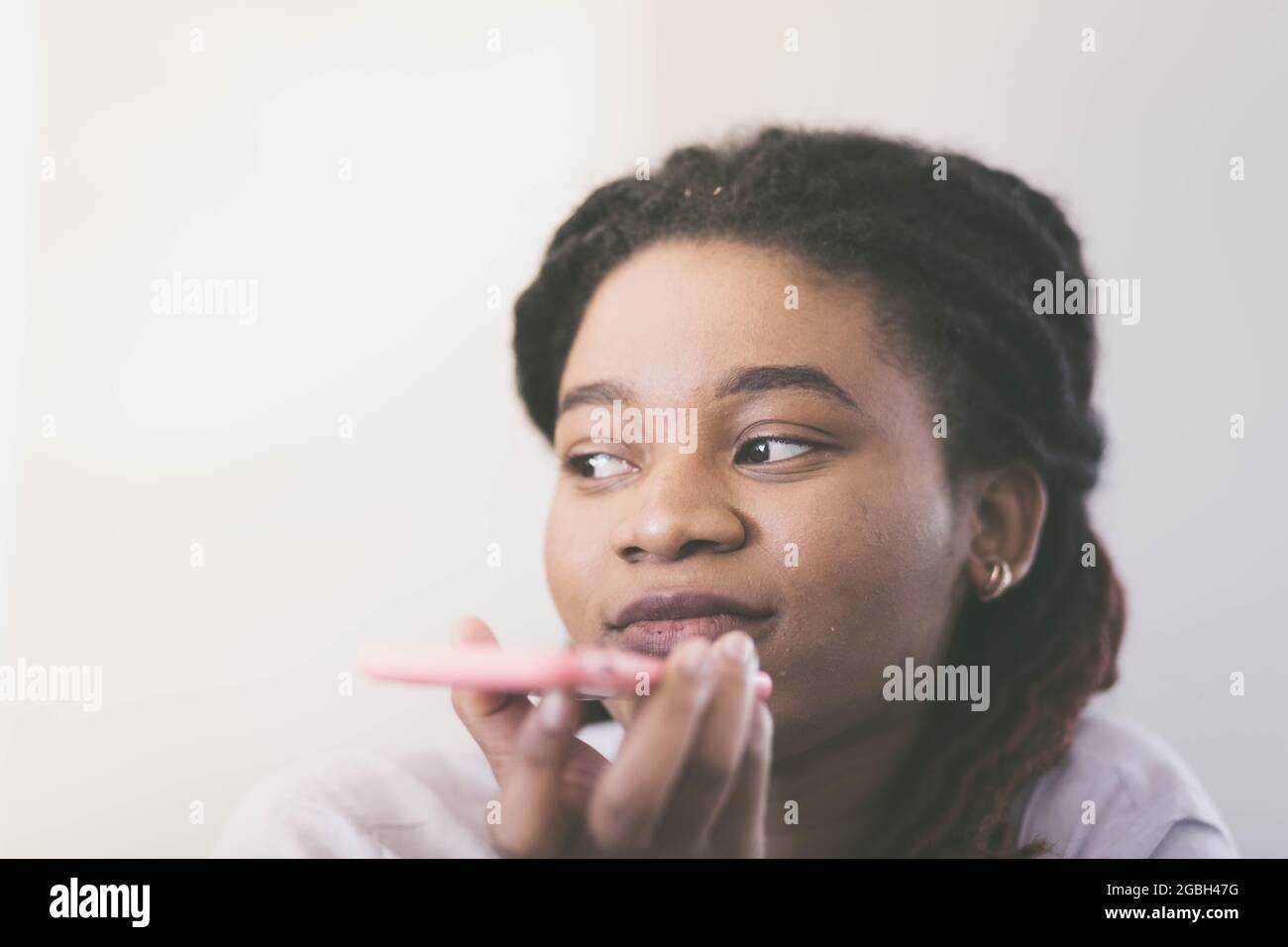 Sad woman of African race speaks by smartphone while holding it in front of face. Color graded Stock Photo