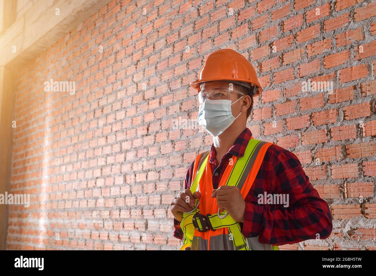 Portrait of a construction worker wearing a protective face mask, hard hat and reflective clothing, Thailand Stock Photo