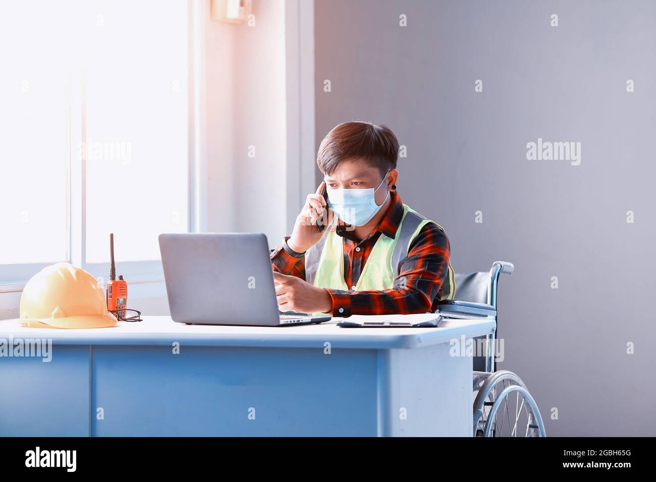 Architect in a wheelchair working at a desk in an office Stock Photo