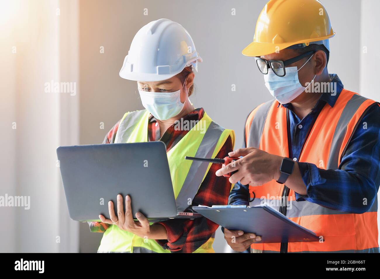 Two architects standing in an office looking at a laptop Stock Photo