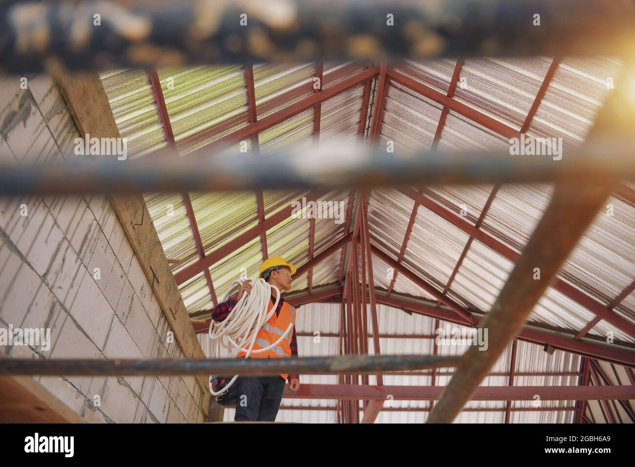 Low angle view of a construction worker standing on a building site carrying plastic pipe Stock Photo