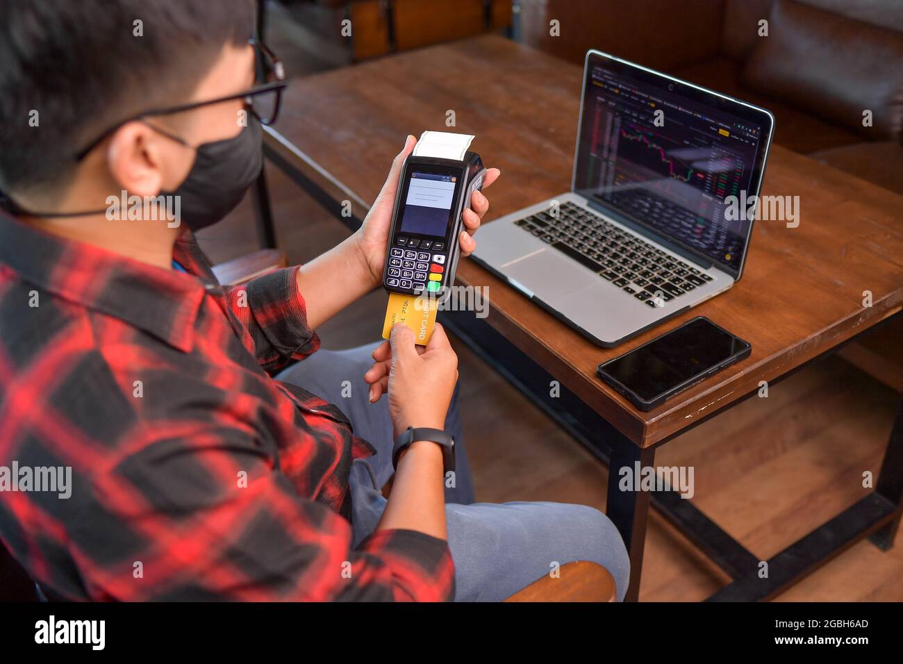 Man sitting at a table making a contactless payment on a credit card reader Stock Photo