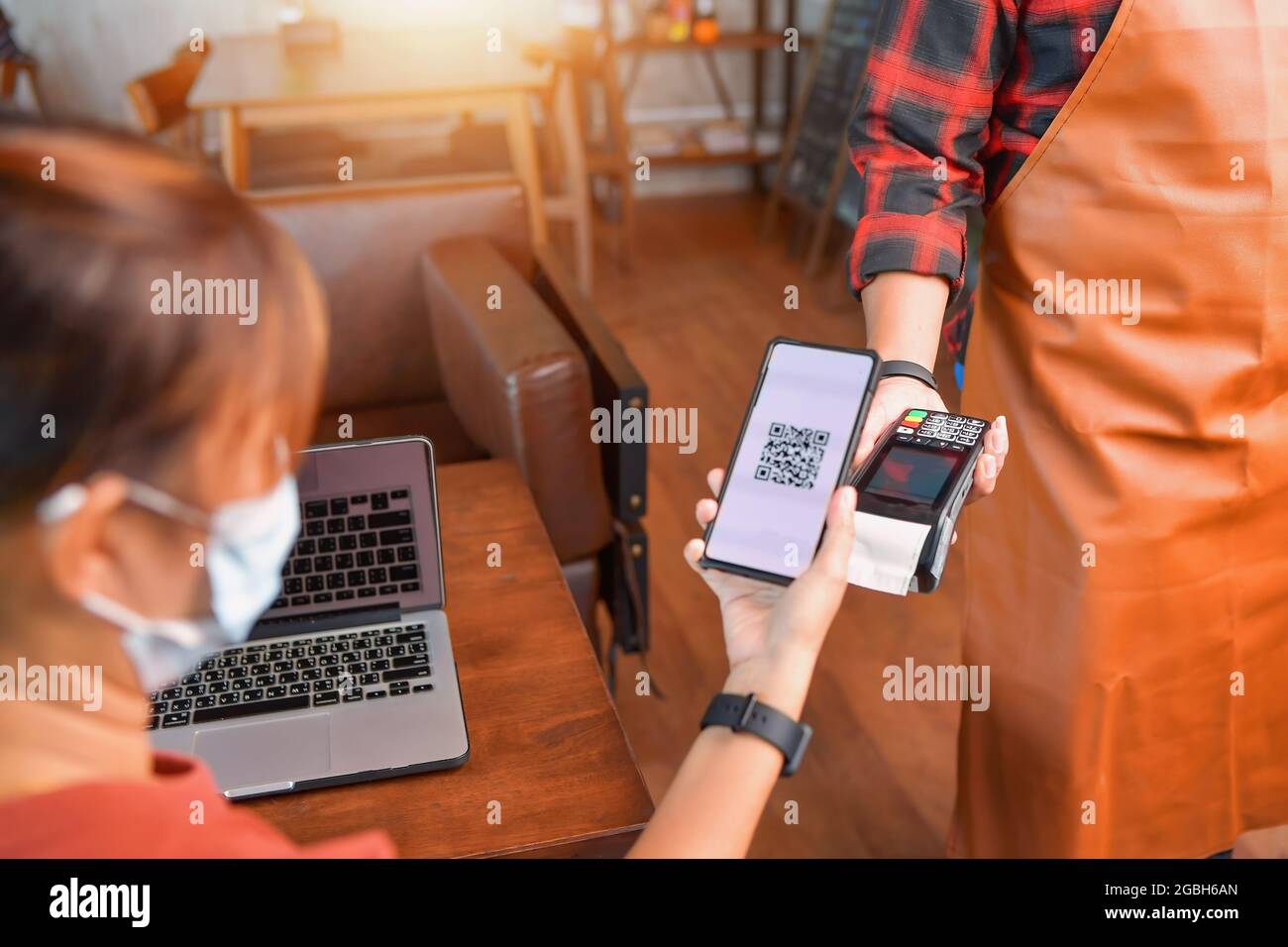 Woman making a mobile payment on a card reader in a cafe Stock Photo