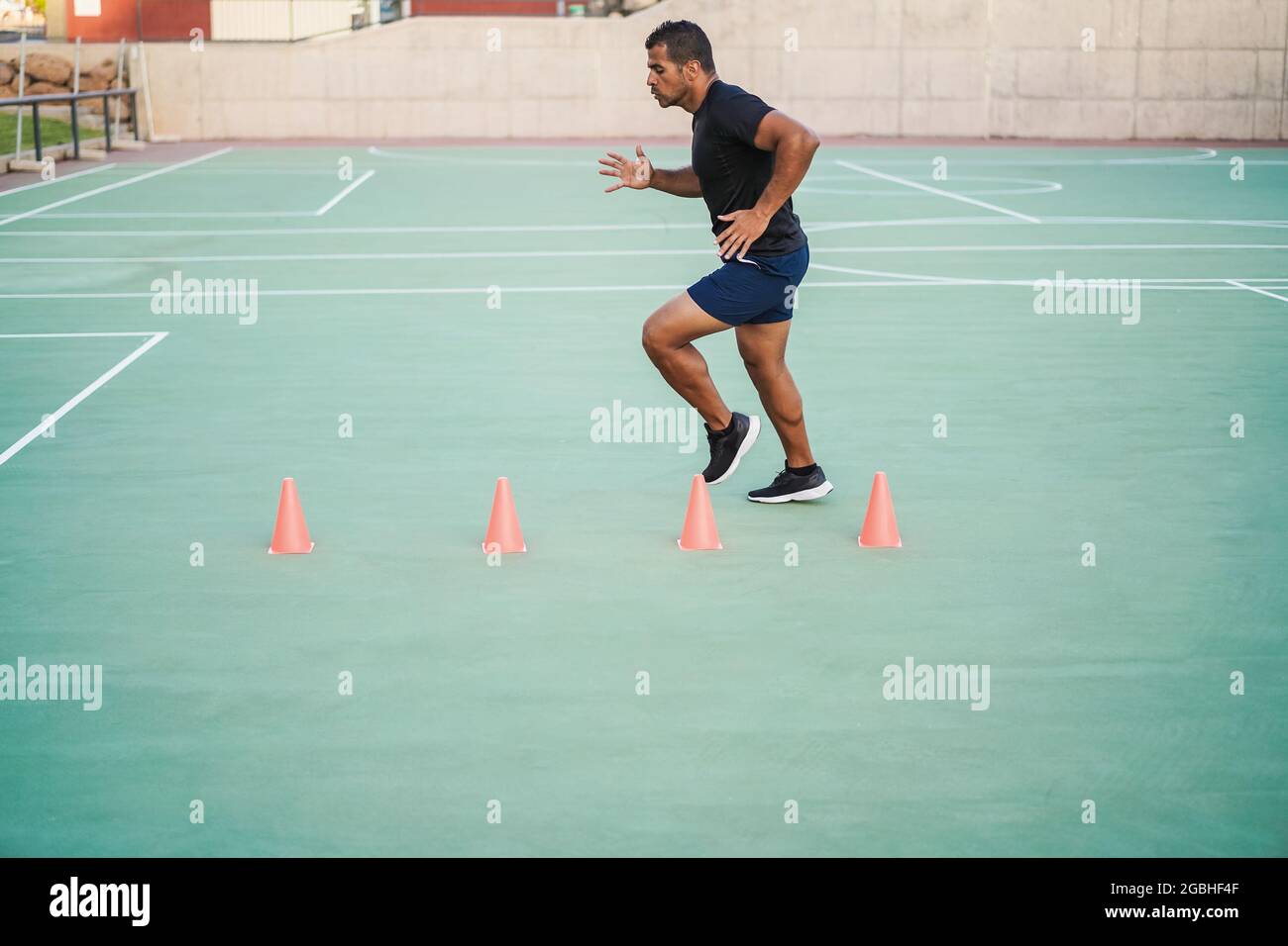 Hispanic man doing speed and agility cone drills workout session outdoors - Focus on man face Stock Photo