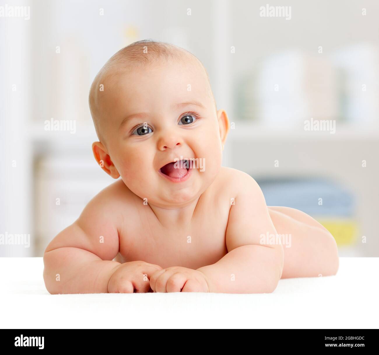 Adorable smiling baby boy lying in bedroom Stock Photo