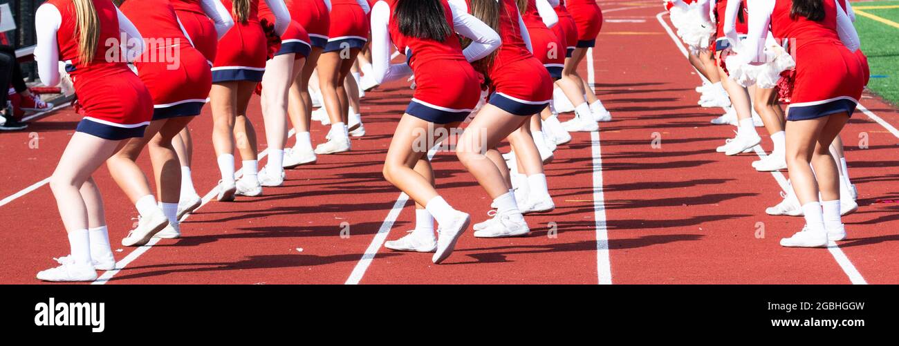 High school cheelearders dancing on the track perfoming for the fans at a football game. Stock Photo