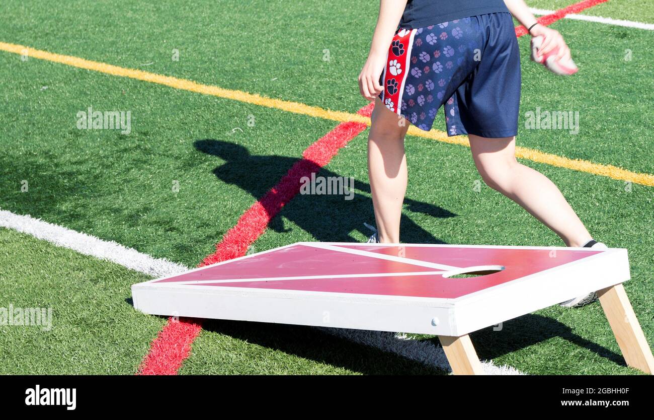 Side view of a teenager about to throw a bean bag while playing