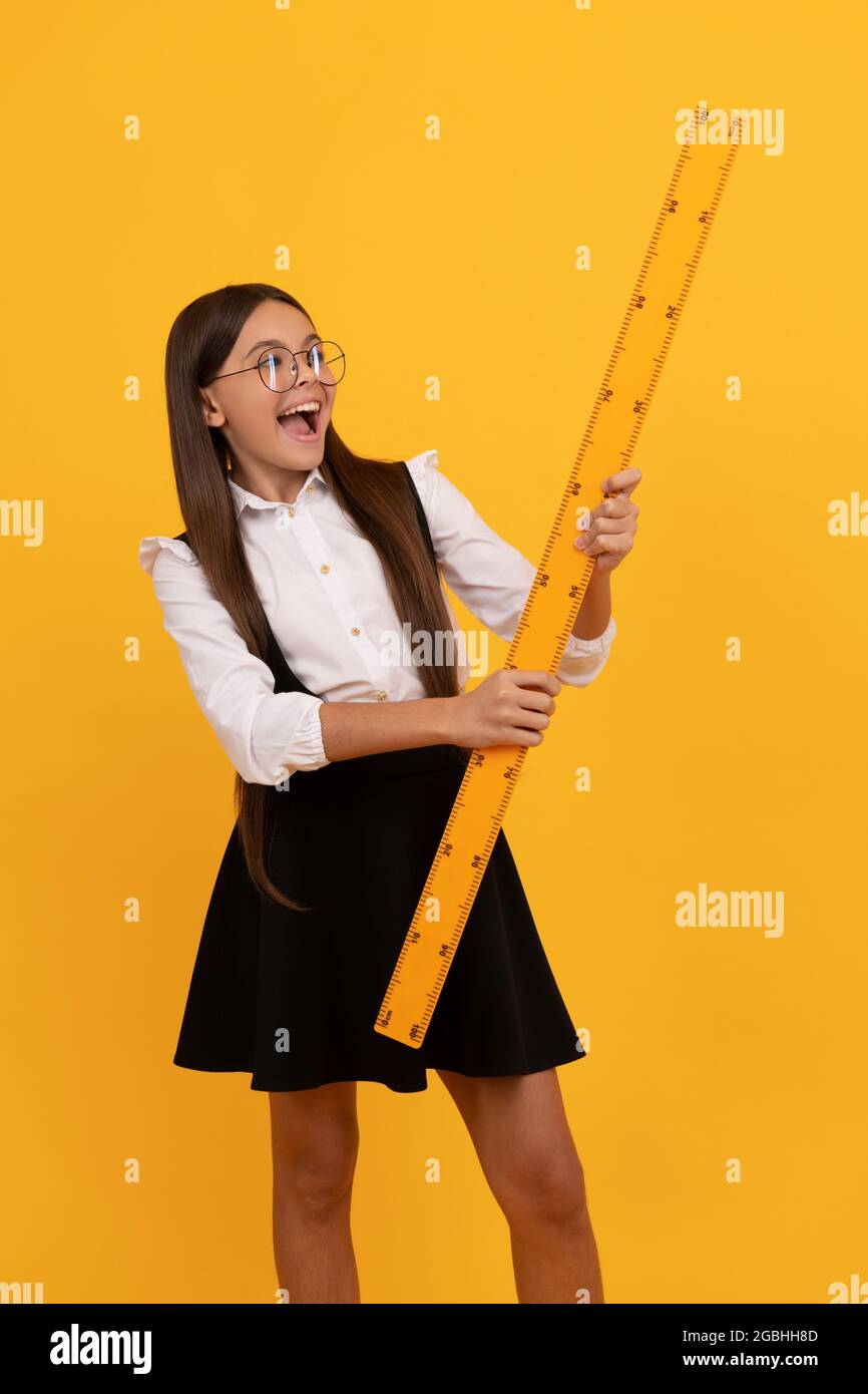 surprised nerd teen girl in uniform and glasses hold mathematics ruler ...