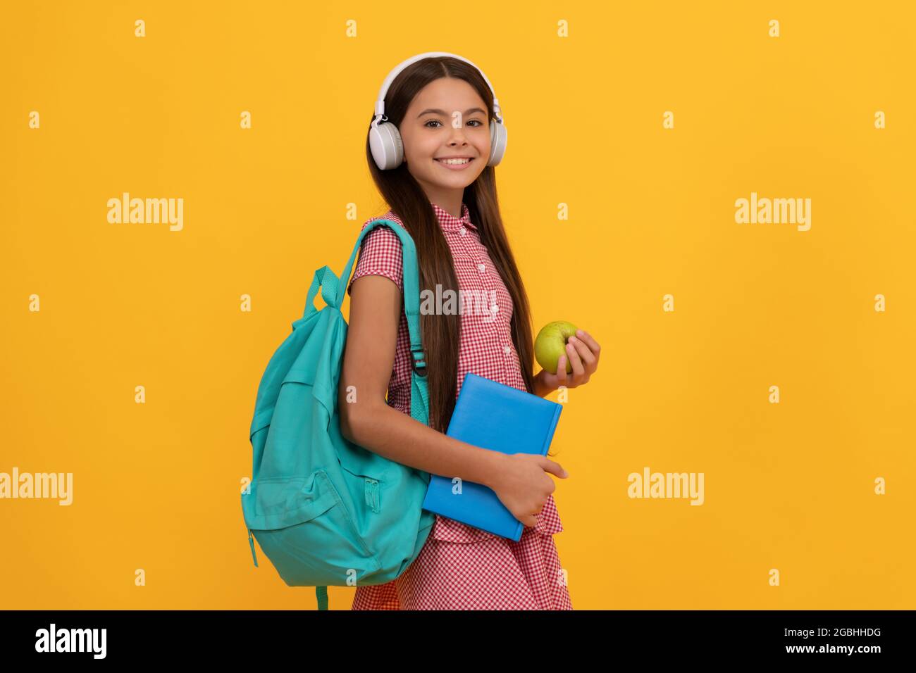 happy school kid in headphones carry backpack and workbook with apple
