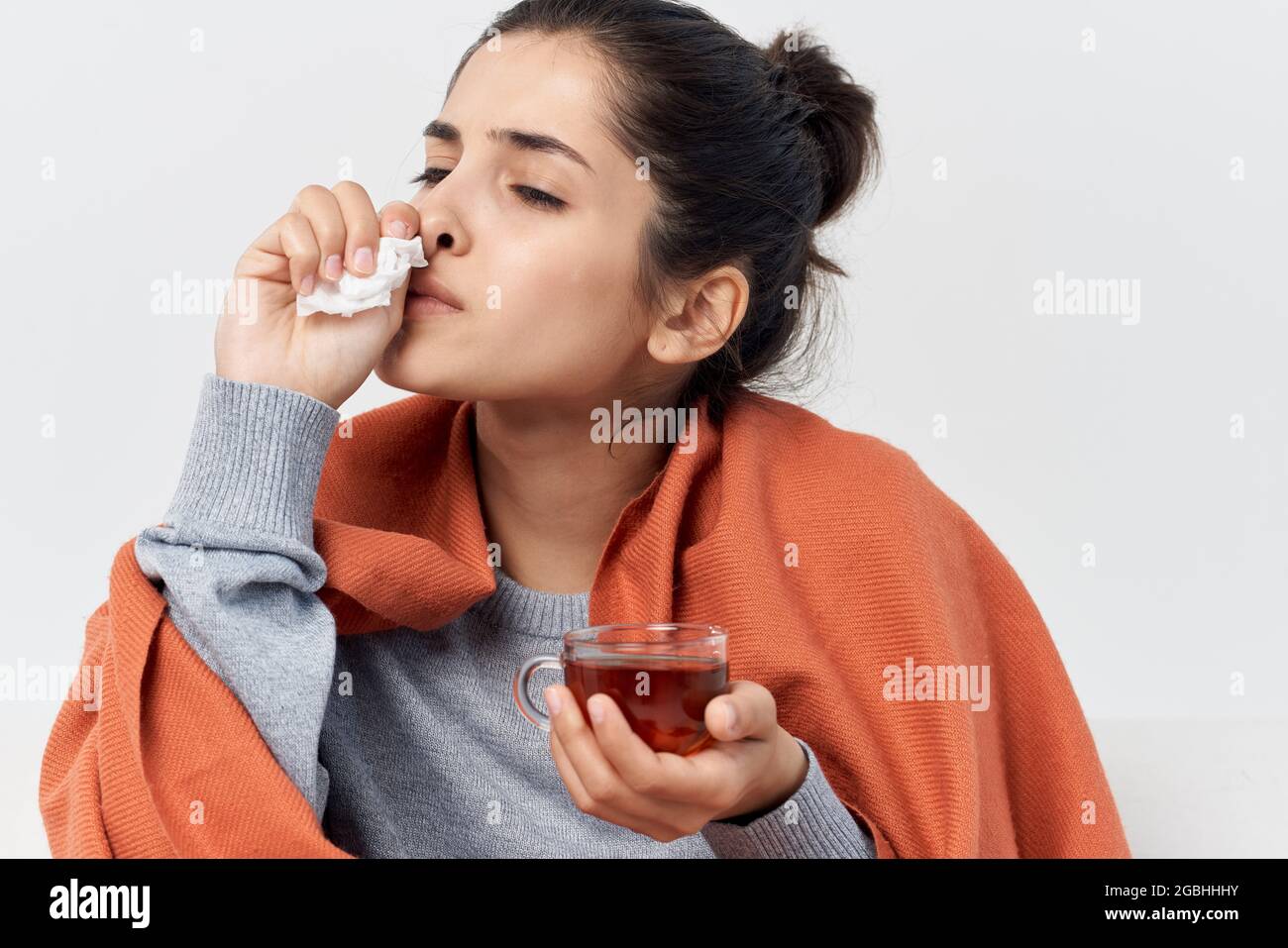 woman with a cup of tea hiding behind a blanket at home cold infection ...