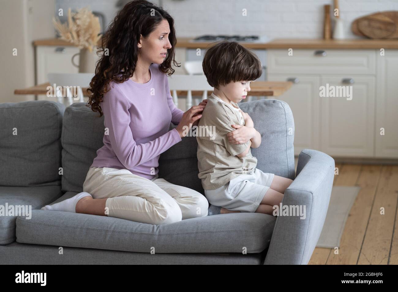 Excusing mother try to make peace with stubborn offended boy kid frowning and ignoring caring mom Stock Photo