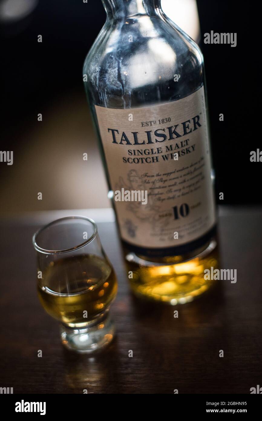 Bucharest, Romania - August 5, 2021: Illustrative editorial image of a single malt Talisker scotch whisky bottle next to a glass on counter in a pub. Stock Photo