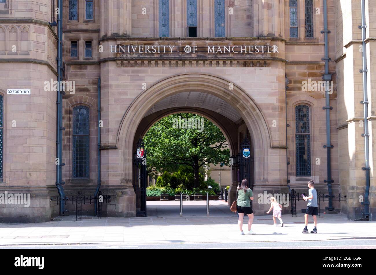 Woman and children look at Whitworth Hall with a sign for the University of Manchester, Manchester, England, United Kingdom. Stock Photo