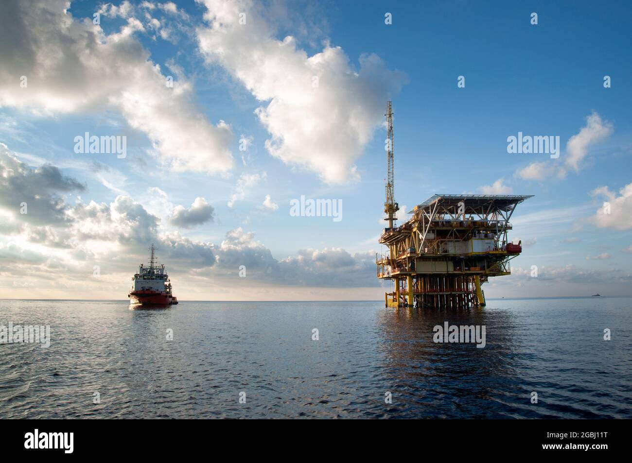 offshore platform drilling at sea during morning with offshore supply vessel Stock Photo