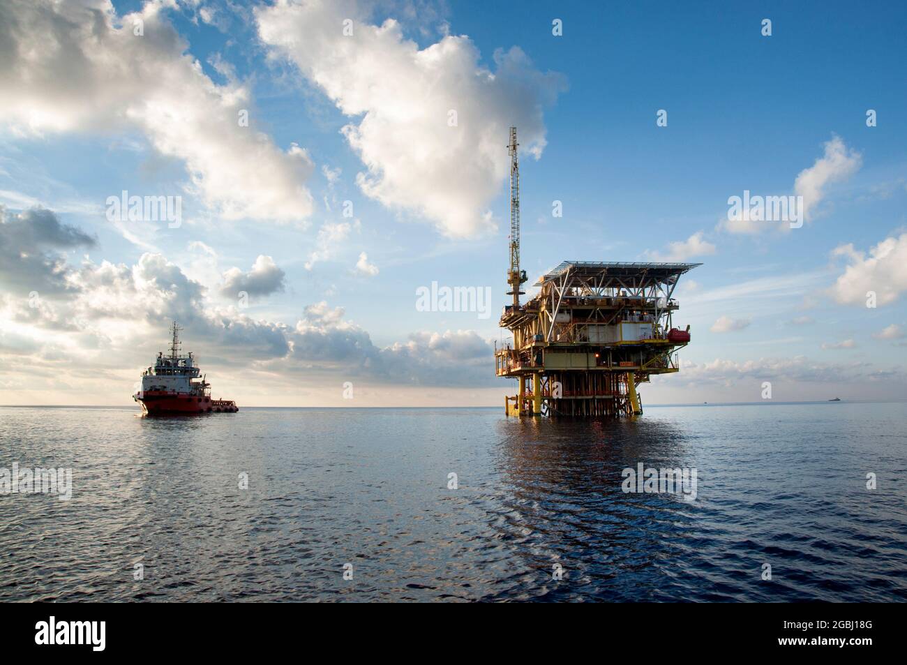 offshore platform drilling at sea during morning with offshore supply vessel Stock Photo