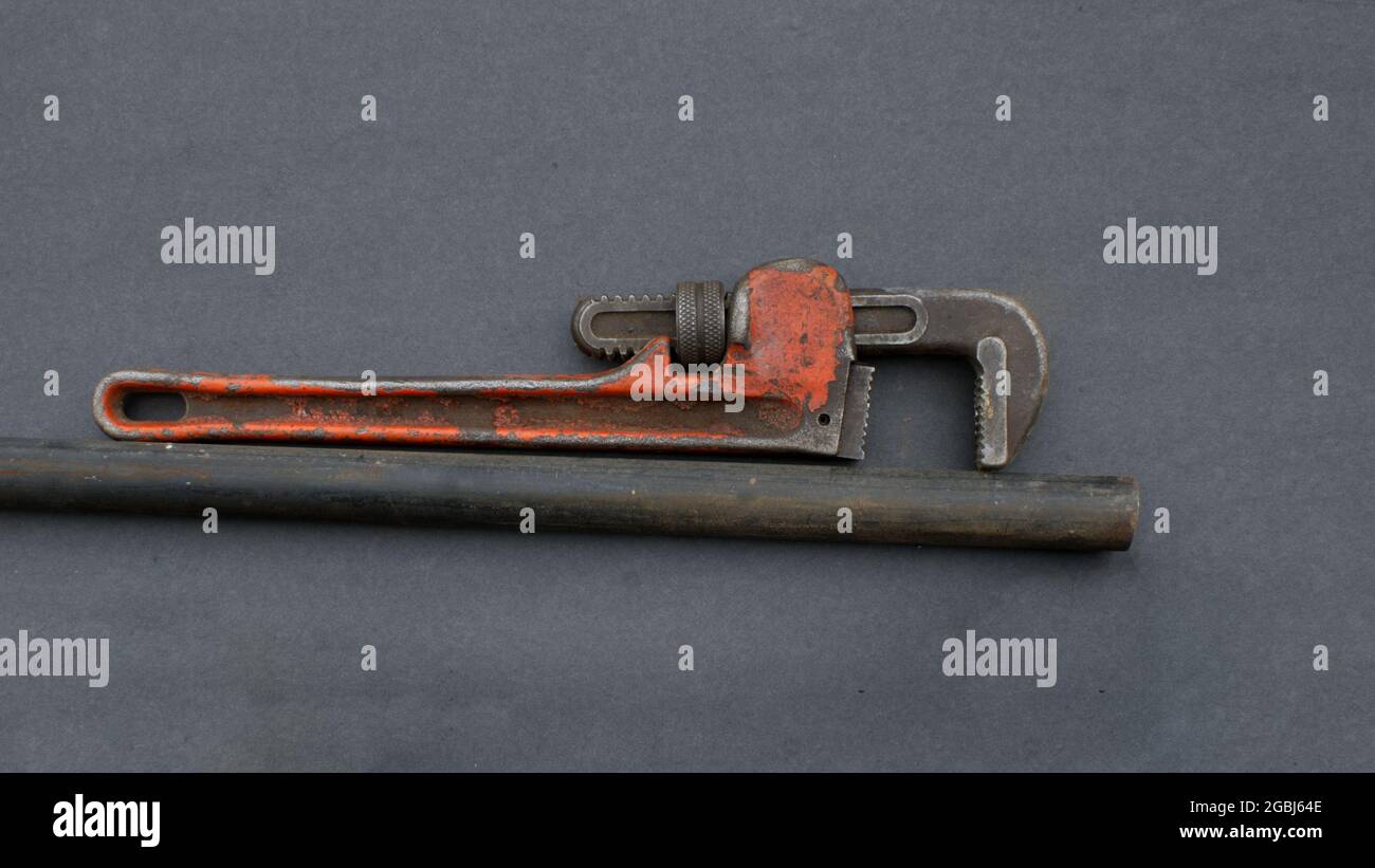 An Old Pipe Wrench and Black Iron Pipe Stock Photo