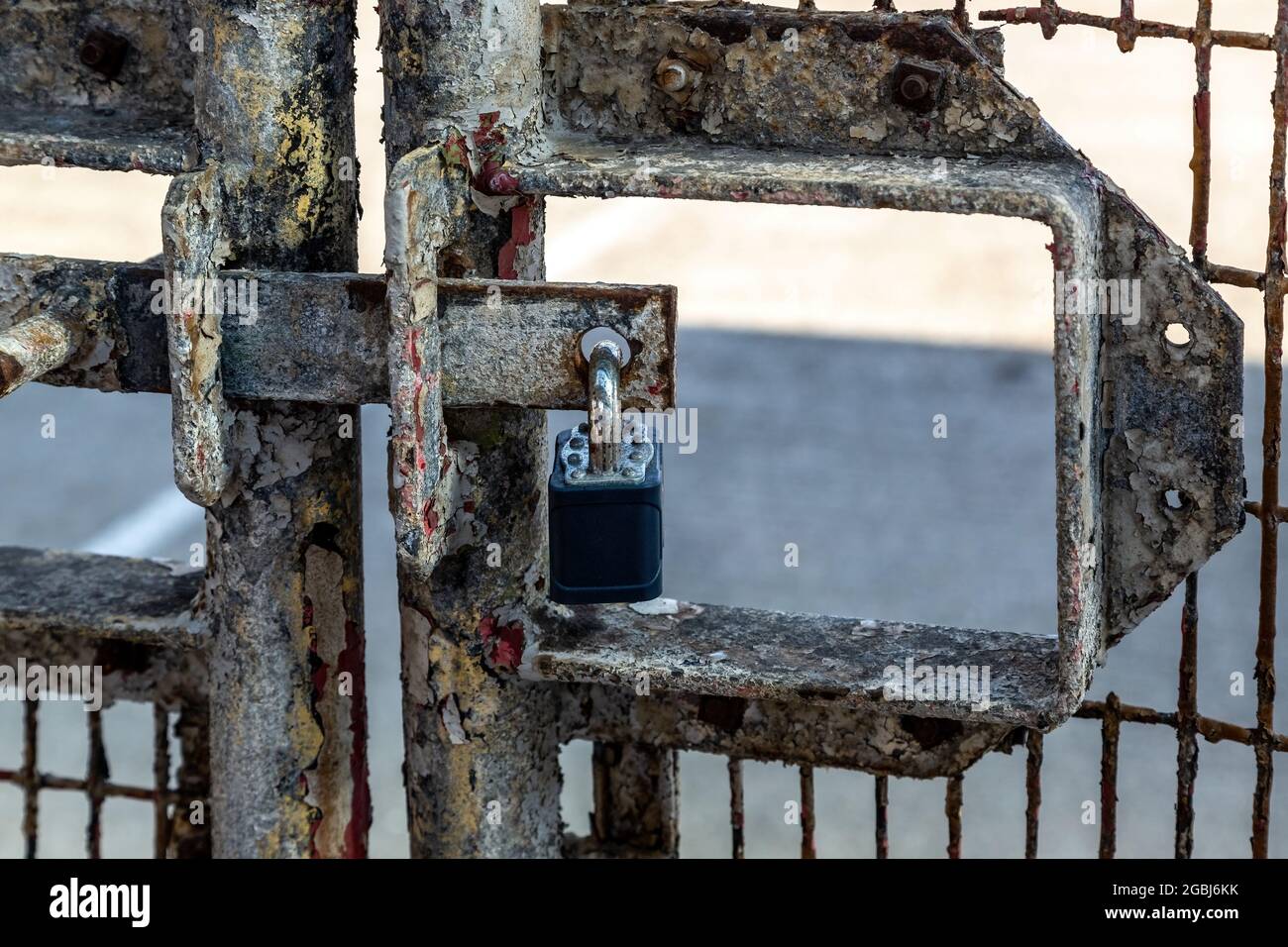 A padlock hanging on an old rusty metal gate Stock Photo